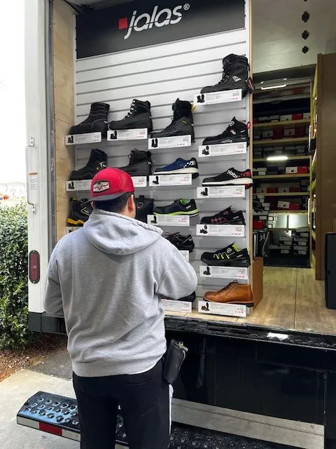 Person standing at the back of a Jalas shoe truck looking at a display of safety shoes.