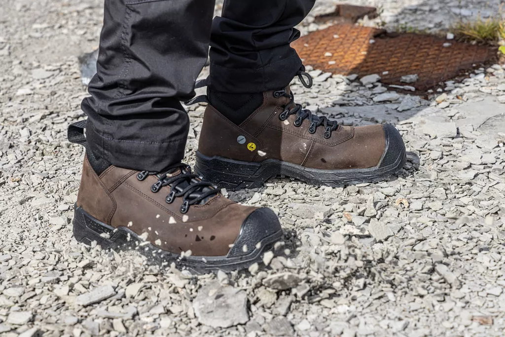 Worker wearing brown JALAS HEAVY DUTY 1218 safety boots on gravel.