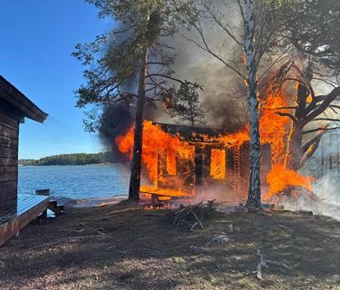 A fire destroying a lakeside storage shed beside a sauna.