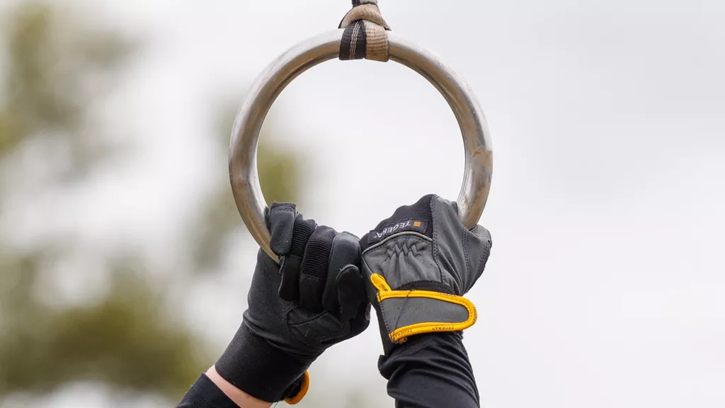 TEGERA 9105 gloves gripping a hanging ring during a Tough Viking obstacle.